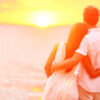 Honeymoon couple romantic in love at beach sunset. Newlywed happy young couple embracing enjoying ocean sunset during travel holidays vacation getaway. Interracial couple, Asian woman, Caucasian man.