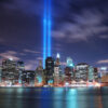 Remember September 11. New York City Manhattan panorama view at night with office building skyscrapers skyline illuminated over Hudson River and two light beam